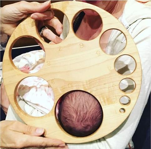 A big wooden planchette with holes numbered 1 to 10 with 10 lined up with a baby’s head to represent 10 cm dilation of the cervix.