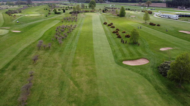An aerial view down a golf fairway at Ludlow Golf Course, the green can be seen in the distance, small bushes line each side of the fairway in the 'rough'