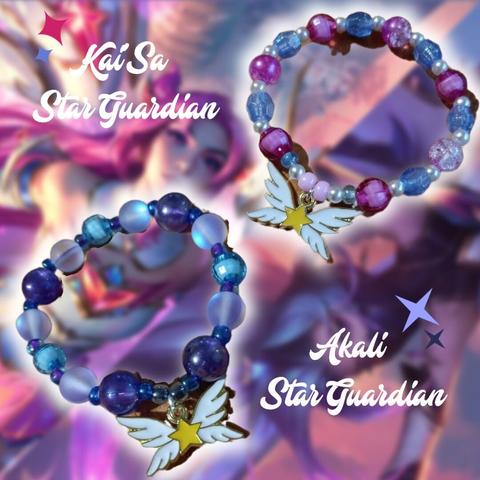 Pulseras hechas a mano de Kai'Sa y Akali Guardianas de las Estrellas, una de tonos rosas, azules y blancos, la segunda azules y morados, las dos con un colgante de una estrella alada