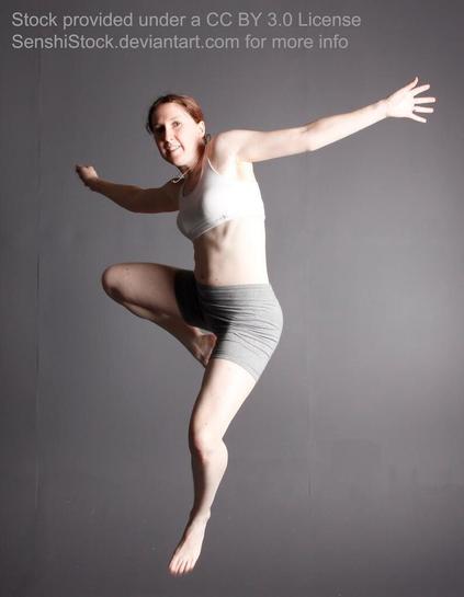A person jumping in the air, both arms outstreched, on a grey background. One knee is up and the other leg is extended.