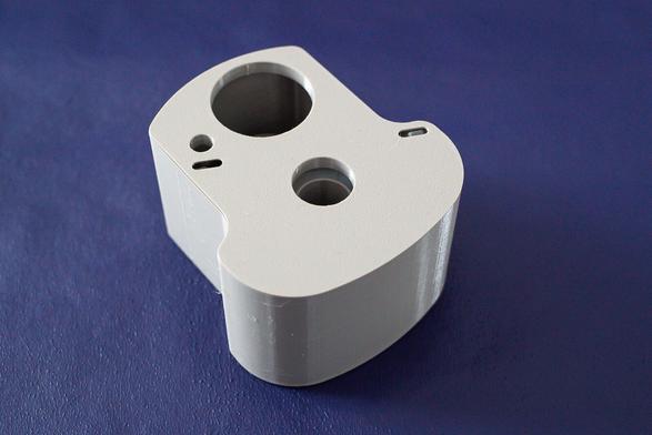 A 3D-printed cleaning fluid cartridge in grey on a violet background.