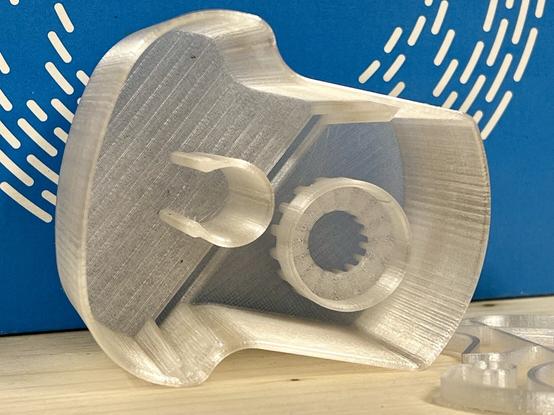 A sustainable 3D-printed cleaning fluid capsule for the Philips smart cleaning system for electric shavers. A transparent print using PCTG on a wooden surface with a blue filament box in the background.