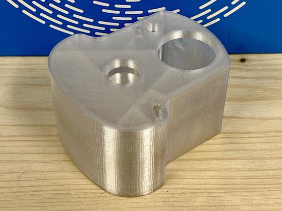 A sustainable 3D-printed cleaning fluid capsule for the Philips smart cleaning system for electric shavers. A transparent print using PCTG on a wooden surface with a blue filament box in the background.