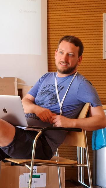 Ein Mann in blauem tshirt und Laptop auf dem schoß