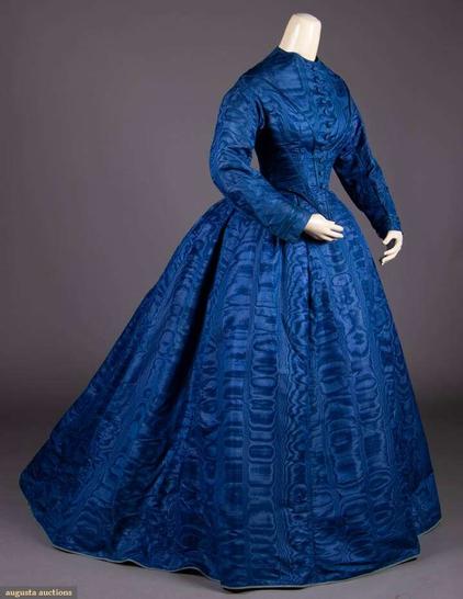 A bright blue dress with a bell-shaped skirt, long sleeves, and a high neckline. It has buttons all the way up from the waist to collar. The dress itself has a wavy pattern on it in lengthwise stripes.