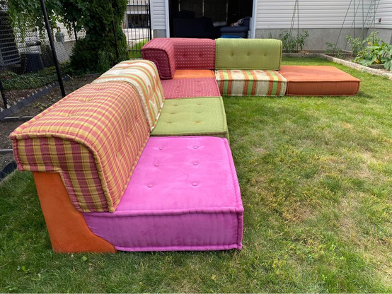 Sectional in a variety of coordinating colours and patterns. Colours include lime green, orange, beige, and red. There are stripes and plaids.