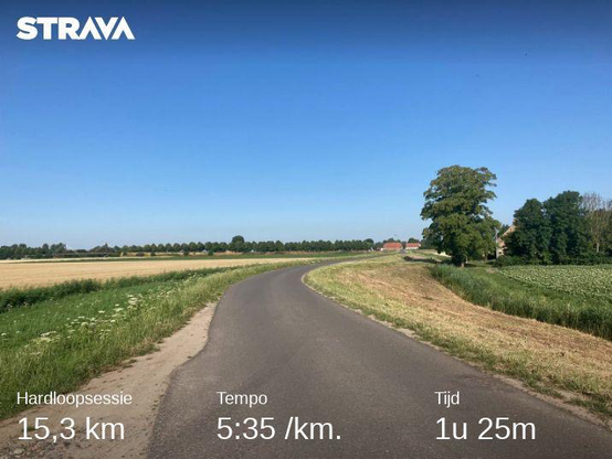 Foto van het buitengebied in Zevenbergen. Je ziet een asfaltweg tussen de weilanden door. De lucht is blauw en de zon schijnt fel. Onderaan de foto staan de statistieken van de training: 15,3 kilometer in een gemiddeld tempo van 5 minuten en 35 seconden per kilometer. Totale duur van de training was 1 uur en 25 minuten