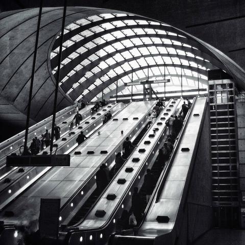A b/w photo of London's Canary Wharf tube station escalators.