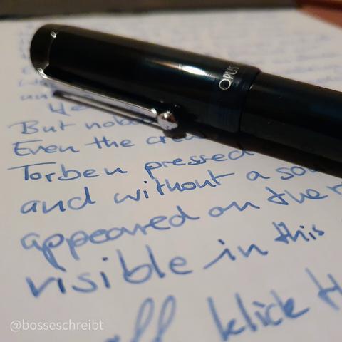 A handwritten Page with a fountain pen laying on top of it. The ink is a light blue and the fountain pen is a dark teal.