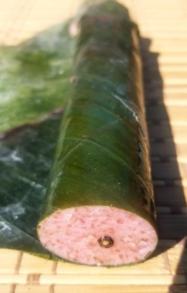 A roll of Nem Chua (Vietnamese Cured Pork), wrapped in banana leaf.