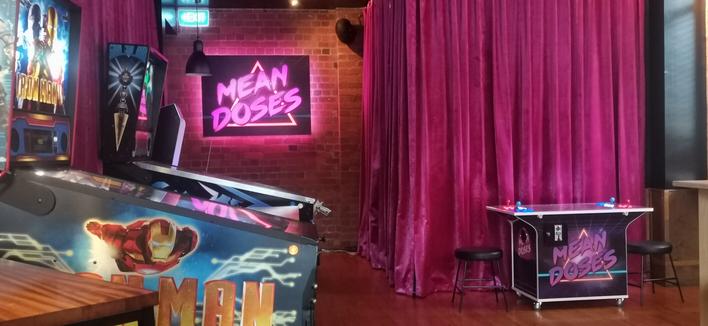Pinball machines, 2 emulator cabs, one being a sit down 2 player, pink velvet curtains, brick walls