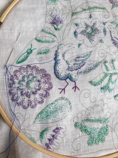Detail of a reproduction seventeenth century embroidery work in progress. The technique is period though not the colours, at least for this kind of work. Birds, an insect and flowers are shaded in speckling stitch, and outlines are beginning to be worked. The corvid in the middle now has feet, sewn in stem stitch.