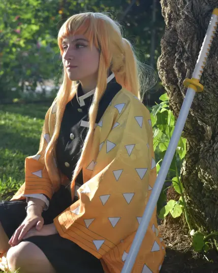 Aparezco con el cosplay de Zenitsu sentada en el césped junto al tronco de un árbol con mi katana reposando al lado