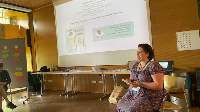 Vortrag einer Frau vor einer Leinwand
