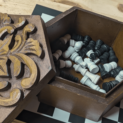 the hexagonal box opens to reveal small black and white wooden pieces.