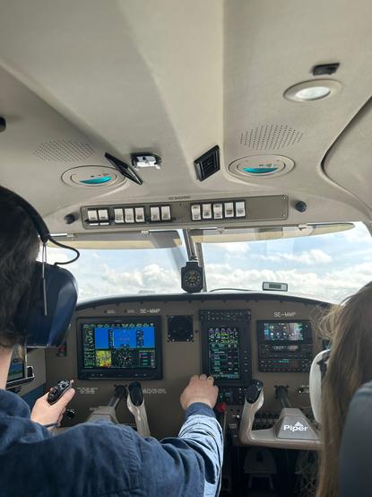 Modernes Cockpit mit Computerbildschirmen in einem einmotorigen Leichtflugzeug, links der Pilot und rechts ein Passagier jeweils halb zu sehen.