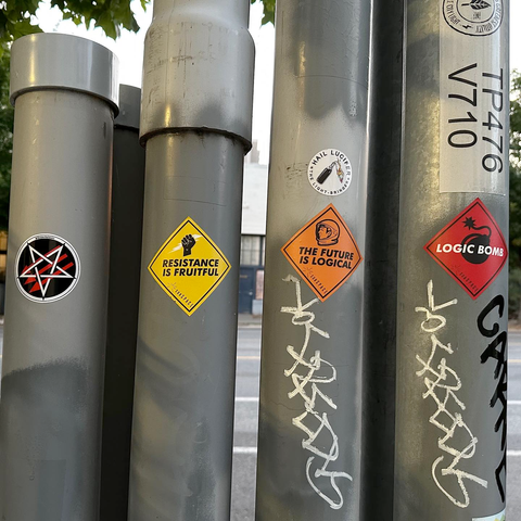 Stickers on poles in a row. Satanic antifascism and hail Lucifer the light ringer (Molotov cocktail) then subSPACE’s “resistance is fruitful”, “the future is logical” and “logic bomb”