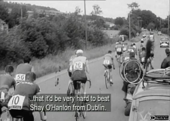 Image of cyclists in the Irish race An Rás. The image may be from 1960. The film is in Irish so the English subtitle reads "that'd it be very hard to beat Shay O'Hanlon from Dublin"