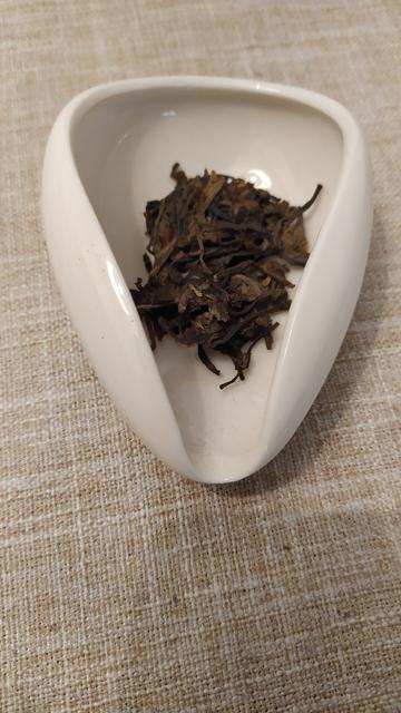 A white chahe (presentation vessel) containing some compacted tea leaves