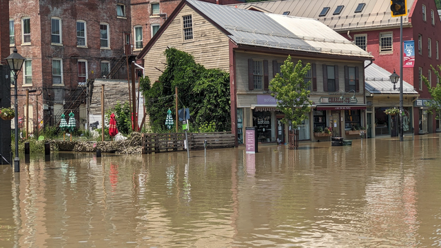 Water engulfs an old wood building with a pub, florist, and umbrellas for outdoor dining.