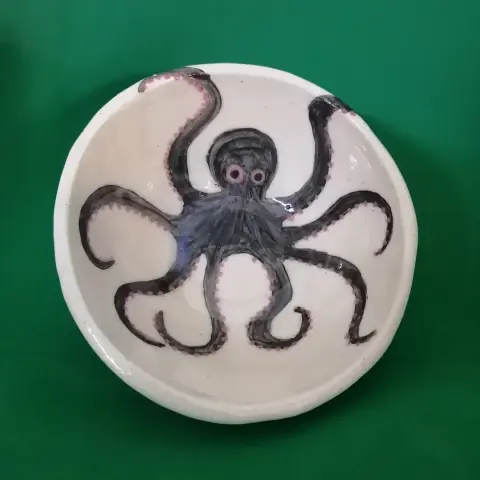 A white ceramic handmade bowl decorated with a black octopus. Seen from above.