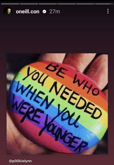 A shot from Con O'Neill's Instagram stories of a hand holding a rainbow-painted rock that says "BE WHO YOU NEEDED WHEN YOU WERE YOUNGER"