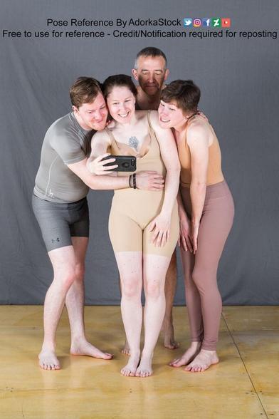 Four people standing close and looking at a cell phone screen. Three of the four are smiling.
