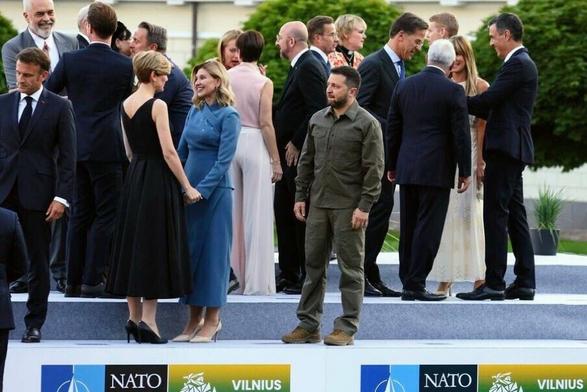 Volodymyr Zelenskyy at a summit, standing on his own amongst a crowd, looking apprehensive