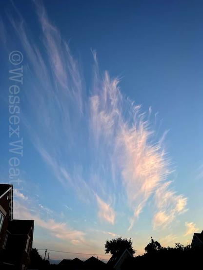 Wispy pink cirrus cloud streaking across the blue sky on an English summer’s evening