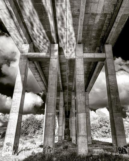 A b/w photo taken underneath the pillars of the Oldenburg A29 motorway bridge over the Hunte river.