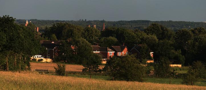 A colour digital photograph of a view across a valley during golden hour in the summer