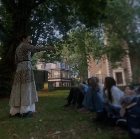 Vanessa in a graveyard with high school students moody dark atmosphere and she is telling them a story