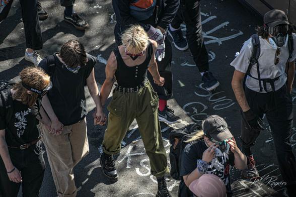 Strong woman in green army fatigues leads small group at Seattle's Capitol HIll BLM protest in 2020.