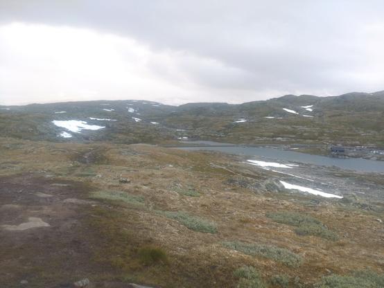 En asfaltert vei går på en steinfylling over et vann i et fjellandskap