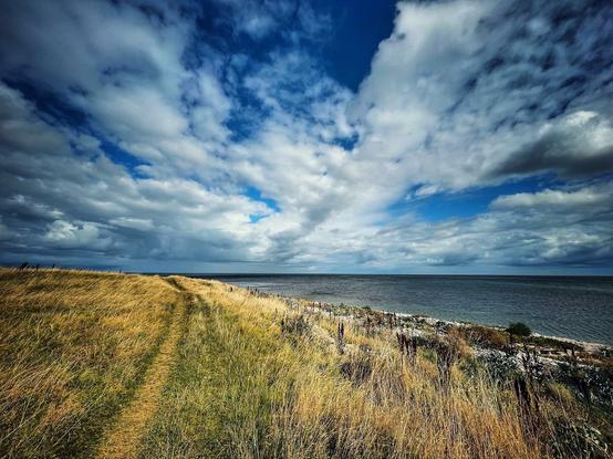 A colourful photo of a dramatic sky and seaside footpath by the Baltic Sea near Grenaa, Denmark.
