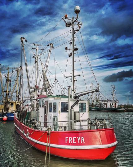 A red-painted crab cutter called "Freya" in the harbour of Dornumersiel, Germany.