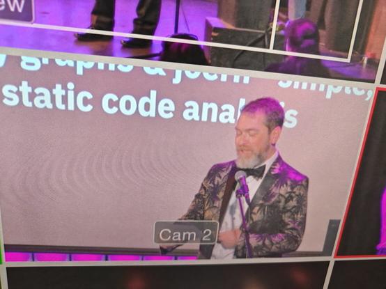 SummerCon host Mr Trumpbour standing in front of a presentation slide in such a way that it reads "static code anal".