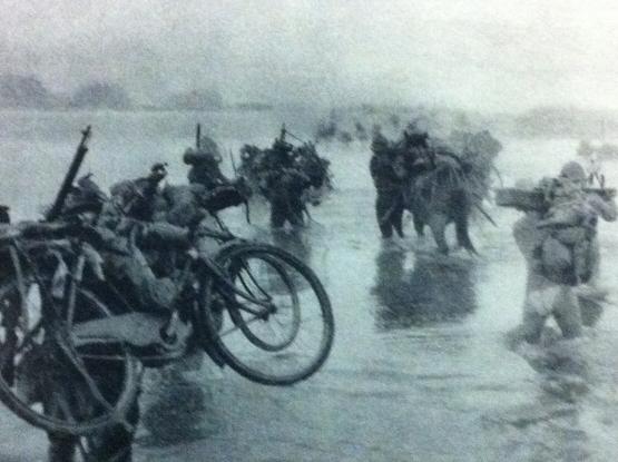 Japanese soldiers crossing water carrying their bicycles
