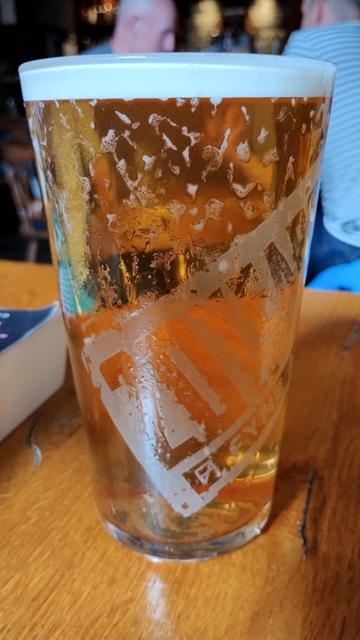 Close up of pint of golden ale, froth dripping down glass