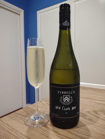 A bottle of Tyrrells 1858 Cuvee Brut wine next to a crystal flute filled with the wine. A delightful pale straw colour.