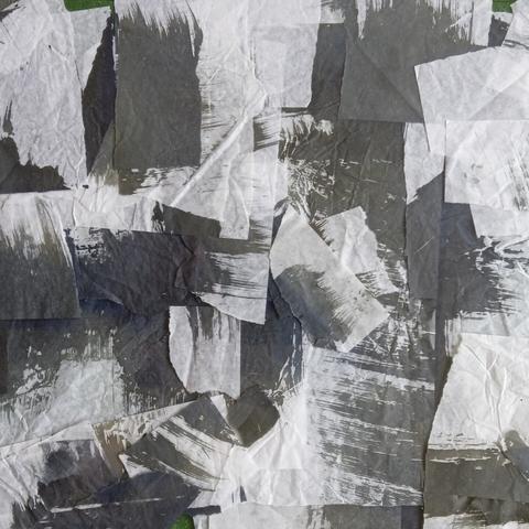 Scraps of white tissue paper with dark painted brush marks. The paper is is multiple layers and there are many scraps