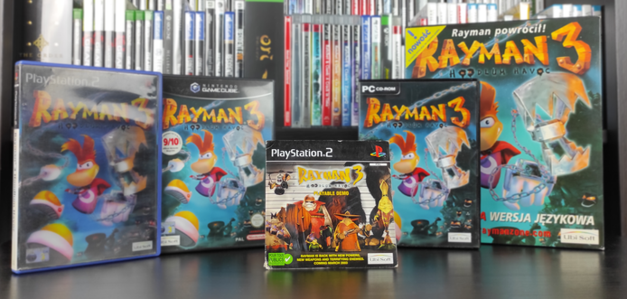 Zdjęcie przedstawia płytę z grywalną wersją demonstracyjną gry "Rayman 3 - Hoodlum Havoc" na konsolę PlayStation 2 stojącą na tle pełnych wersji "Rayman 3 - Hoodlum Havoc" na różne platformy - od lewej: premierowa wersja na PlayStation 2 z trójwymiarową okładką, wersja na Nintendo Gamecube, PC oraz BigBox z polskiej wersji PC-towej.