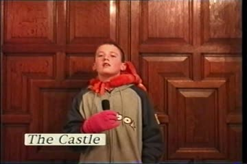 Opening frame of video showing a boy standing in front of the Castle's double wooden doors.