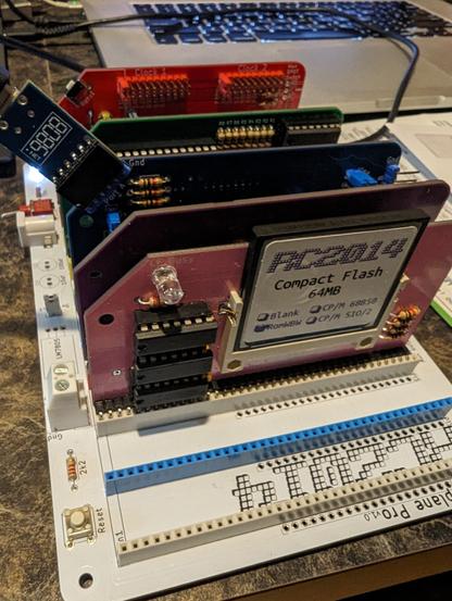 A photo of the current state of the RC2014 build with the newly inserted pink CF card module in good working order. The other modules installed are the purple Z80 CPU, the blue SIO/2, the green 512k RAM/ROM, and the red Dual Clock modules. The colors of the Zed Pro Pride's rainbow are coming together.