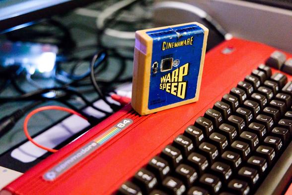 Image of the original Warp Speed cartridge from 1988 as shown on Obliterator918's Commodore 64 Project Haven.

A beige cartridge with a blue label sits on a red Commodore 64 computer.  This cartridge has a switch on it and bears the Cinemaware logo.