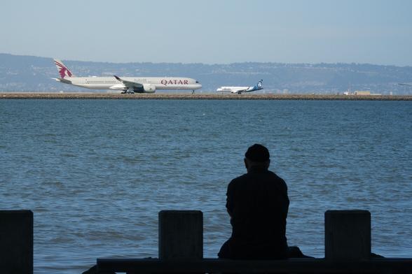A man watching the runway across the water