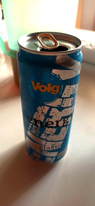 Eine blaue geöffnete Dose Energy Drink von "Volg" auf einem Tisch.