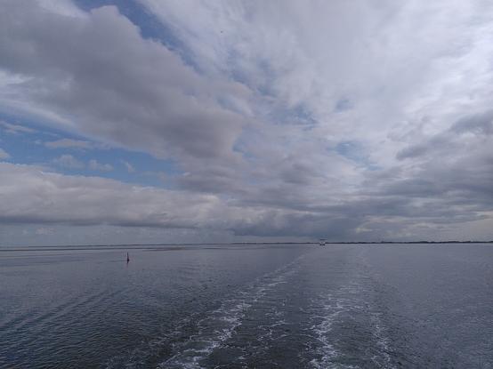 Wasserfläche mit Wolken und einer sehr flachen Küstenlinie
