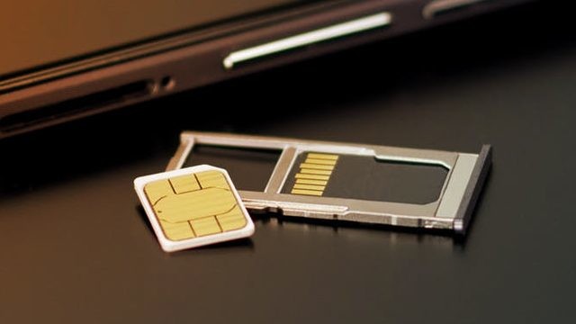 A photo of a SIM card, SIM tray and a smartphone