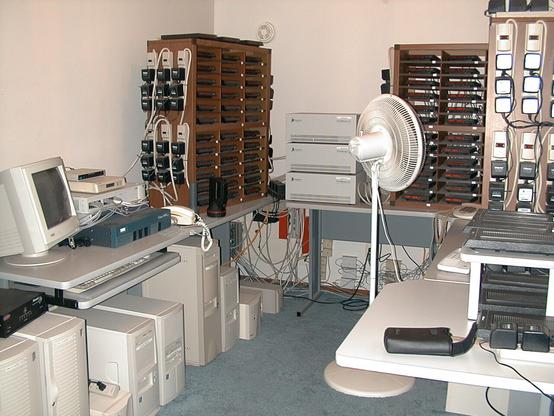 A small room filled with beige computer towers, networking equipment, and racks of Courier modems.